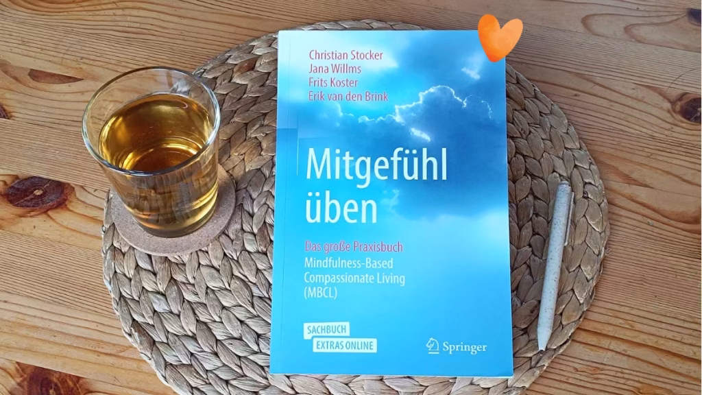Buchcover "Mitgefühl üben - das große Praxisbuch MBCL" mit dunklen Wolken, hellem Sonnenlicht und weitem Himmel.